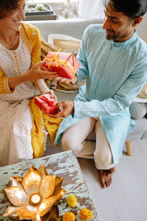 Man and Woman Exchanging Gifts While Sitting on a Sofa