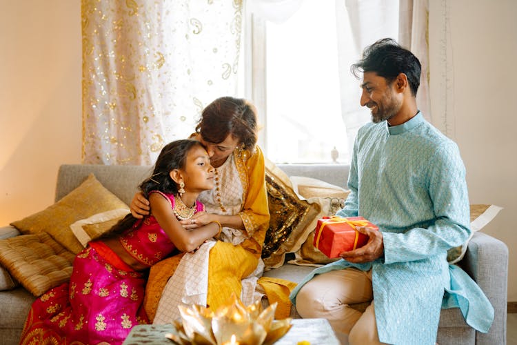 A Happy Family Sitting On The Couch While Wearing Their Traditional Clothes