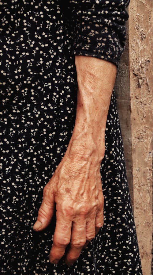 Close up of a Senior Womans Hand and Patterned Dress Fabric