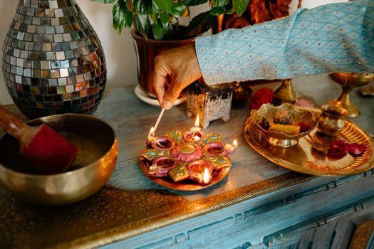 Hand lighting a decorative diya for an Indian festival celebration.
