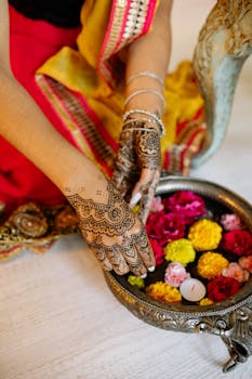 Hands with henna designs arranging colorful flowers for Diwali festival celebration.