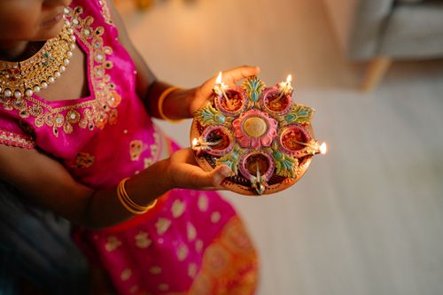 Free A young girl in traditional attire holds decorative Diwali lamps, spreading light and celebration. Stock Photo
