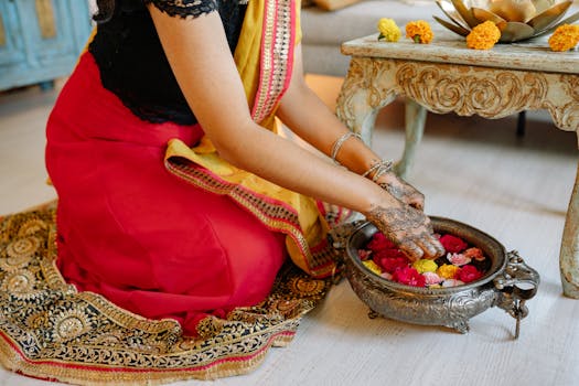 Indian woman in sari performing a traditional floral offering indoors, celebrating cultural festival.