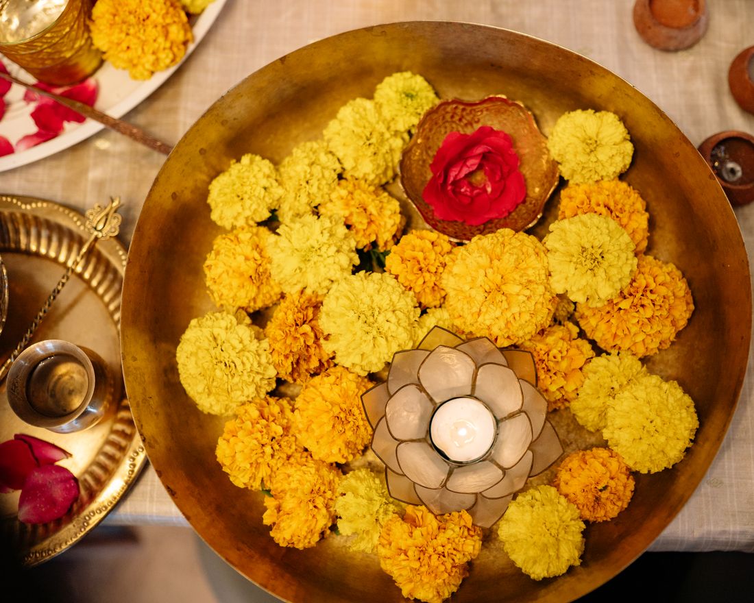 Brass urli filled with marigolds and a floating candle