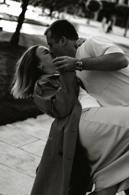 Free Black and white photo of a couple sharing a romantic kiss on a city street. Stock Photo