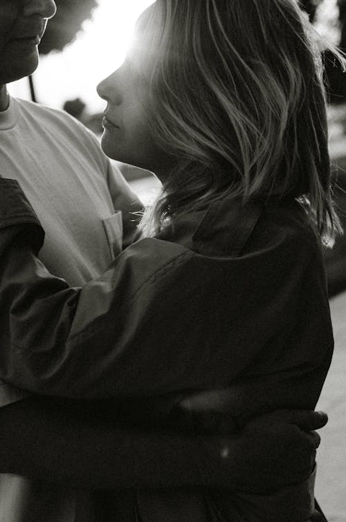 Grayscale Photo of Woman Hugging a Man