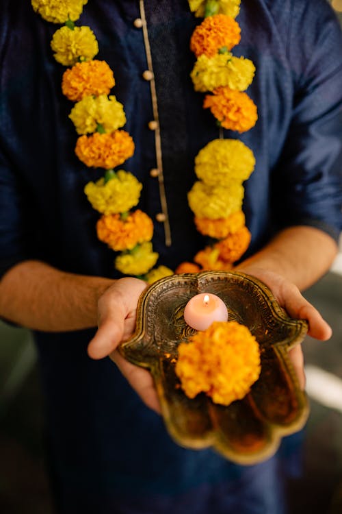 Free Man Holding a Tray with Yellow Flower and a Lighted Tealight Candle Stock Photo
