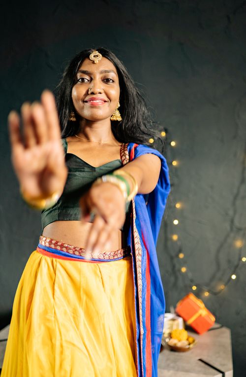 Free Smiling woman in vibrant traditional Indian outfit celebrating indoors with festive lights. Stock Photo