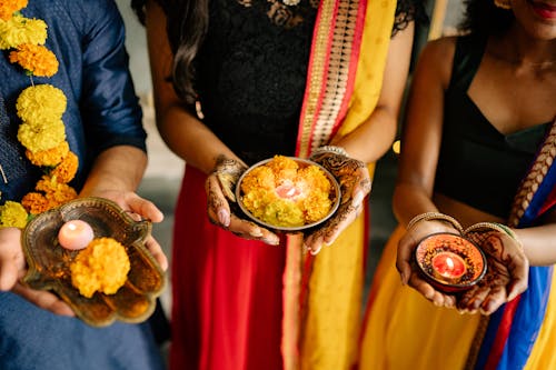 Two Women and a Man Holding Candles Celebrating Diwali