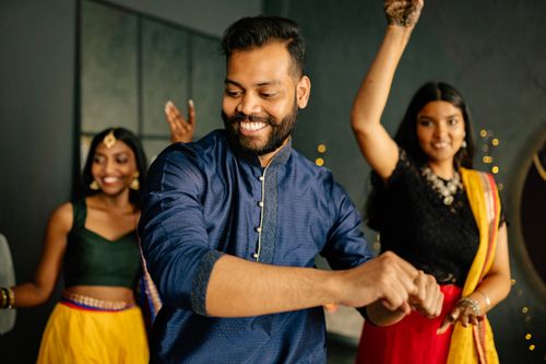 Free Group of people dancing joyfully during a festive Indian celebration indoors. Stock Photo