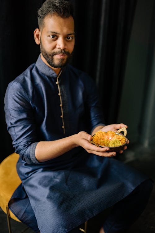 Man in Blue Dress Shirt Holding a Brass Bowl