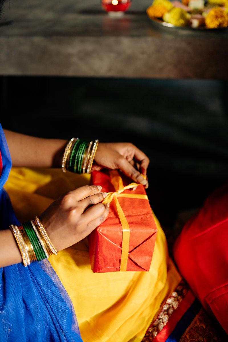 Hands tying a satin ribbon on a red corporate Diwali gift box at Bafna Promoters