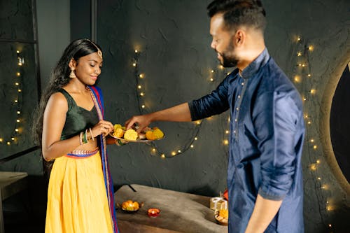 Free Woman Treating a Man to a Traditional Indian Dessert  Stock Photo