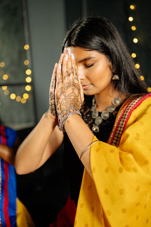 Free South Asian woman praying with henna designs during a festive Diwali celebration. Stock Photo