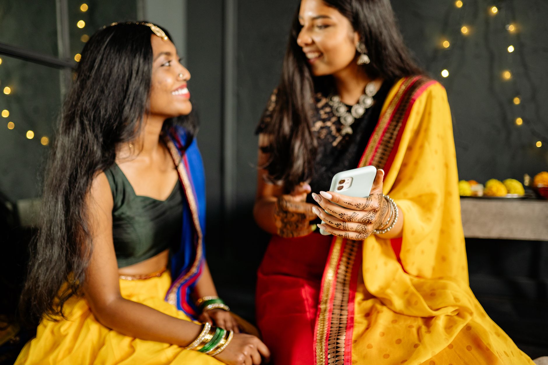 A smartphone displaying South Asian card game apps beside a calculator and handwritten budget, serious home setting