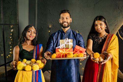 Free Smiling people in traditional Indian attire holding gifts and marigold flowers for a festive celebration. Stock Photo
