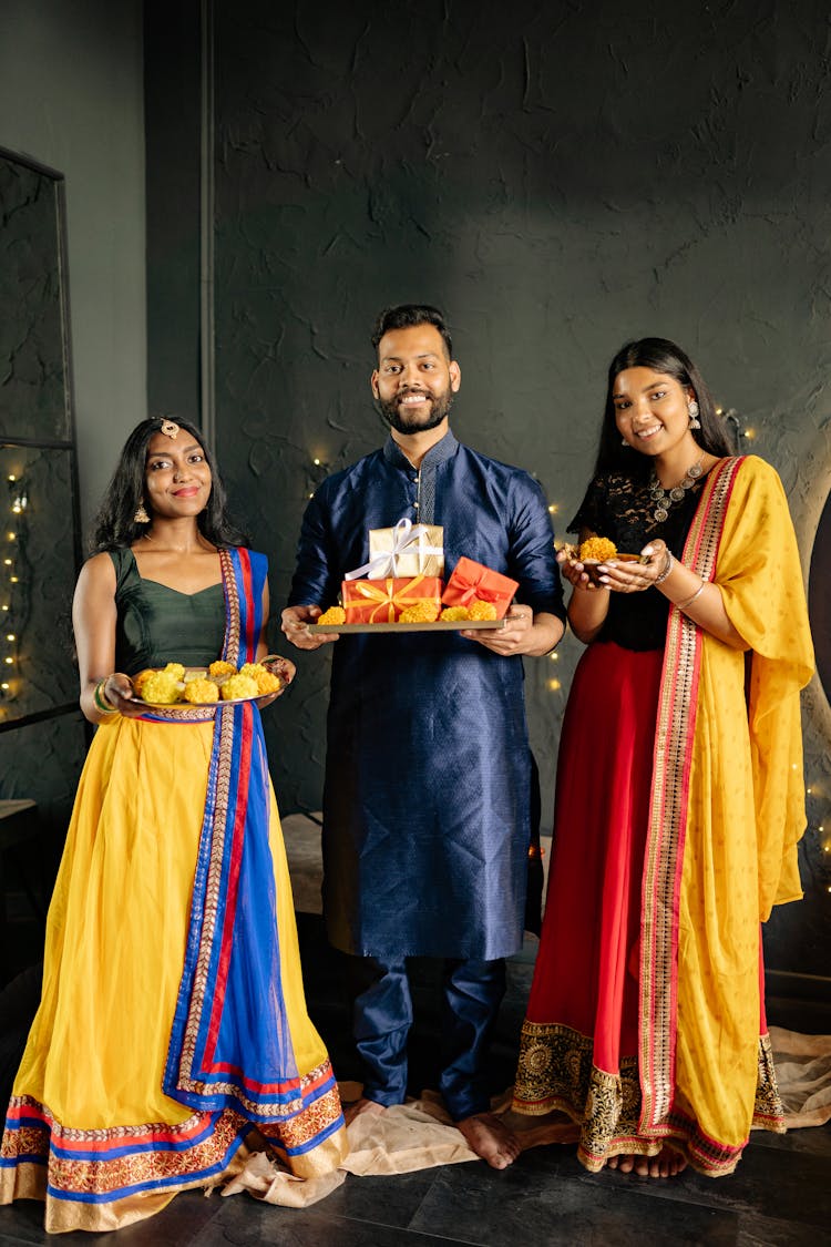 Father And Daughters Holding Presents On A Tray Wearing Their Traditional Clothes