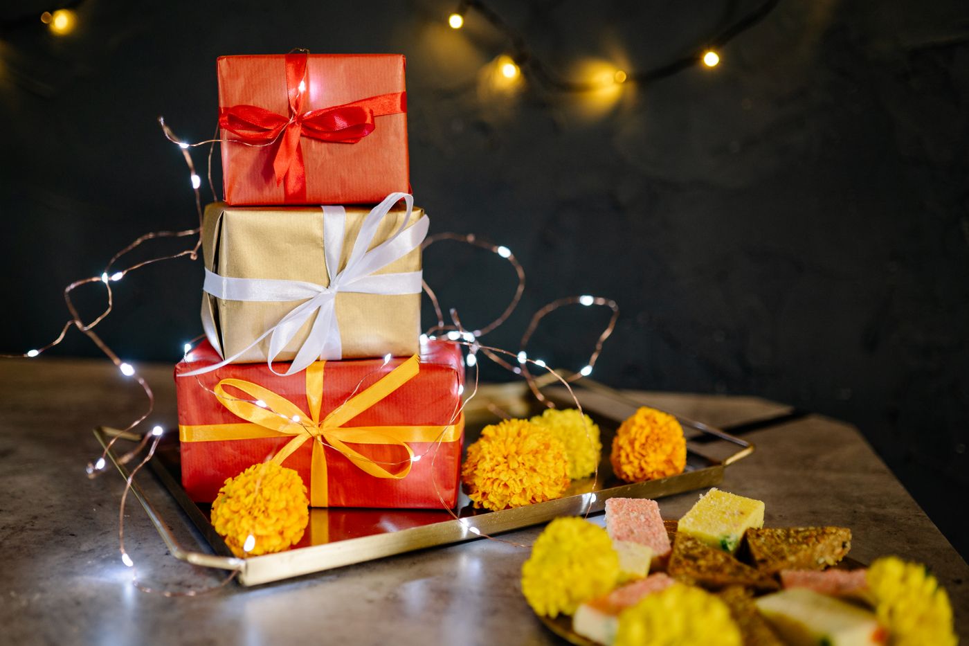 Colourful wrapped gifts on a tray with marigold flowers for Diwali