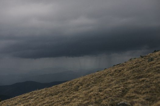 A dark, moody landscape of storm clouds over the Altai mountains, creating a dramatic natural scene.