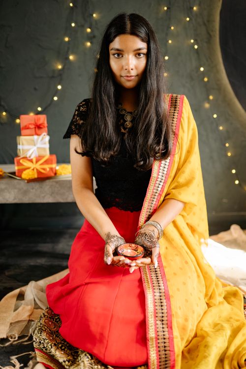 Free Captured moment of a young woman in a traditional saree holding a diya during Diwali celebrations. Stock Photo