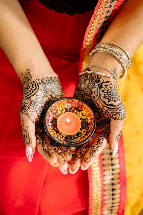 Free Beautiful mehndi decorated hands holding a lit candle during a Diwali celebration. Stock Photo