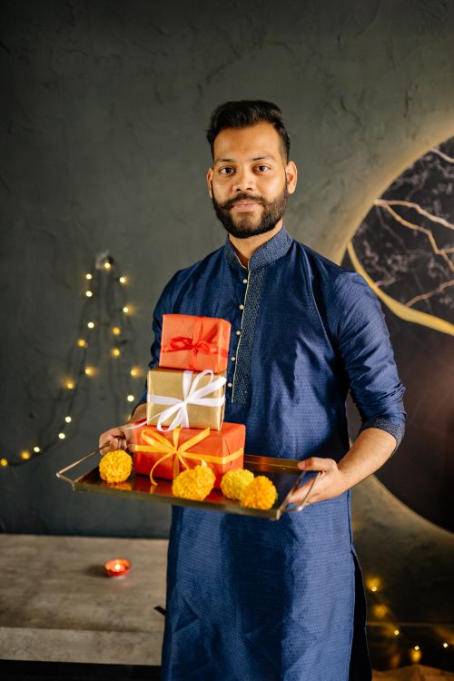 Free Man in traditional attire holding gifts during Diwali celebration, with festive decor. Stock Photo