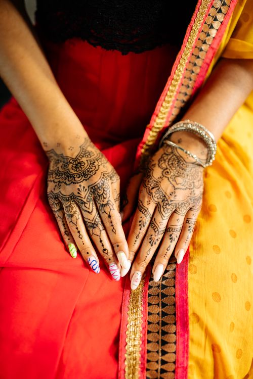 Free Close-up of intricate henna designs on hands with vibrant traditional attire. Stock Photo