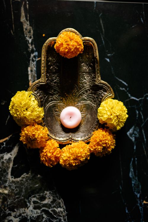 Free Decorative tray with candle surrounded by vibrant marigold flowers on a dark surface. Stock Photo