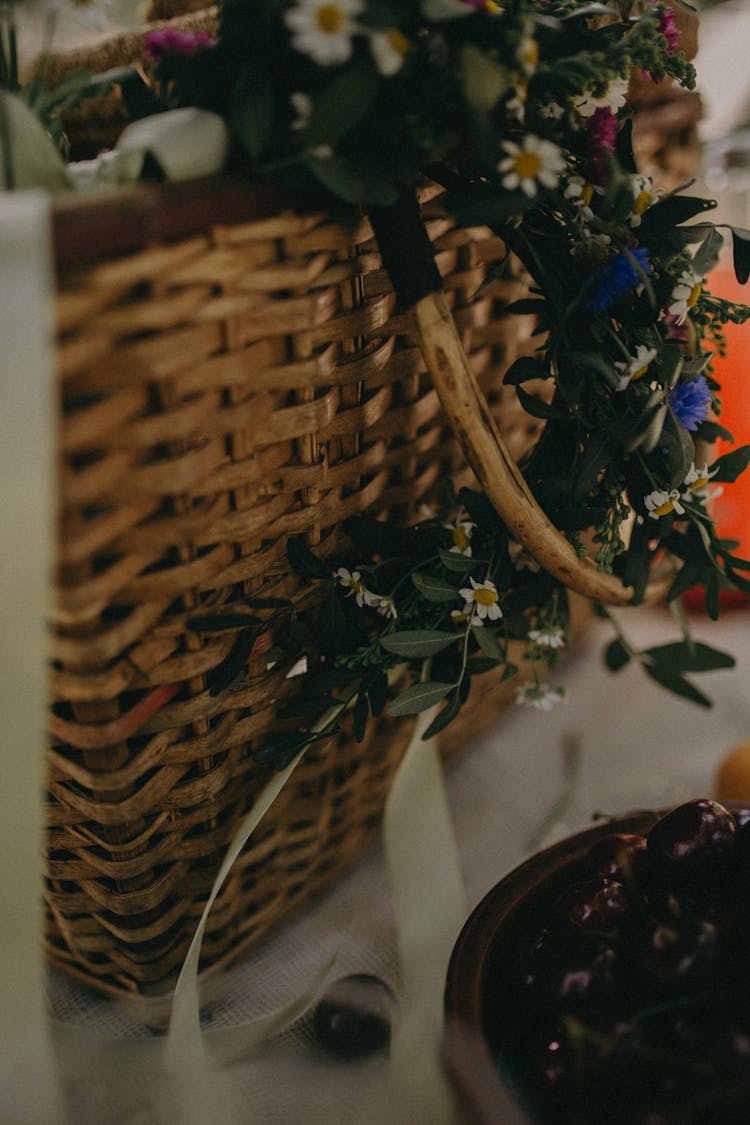 Wicker Basket With Flower Wreath Placed On White Surface