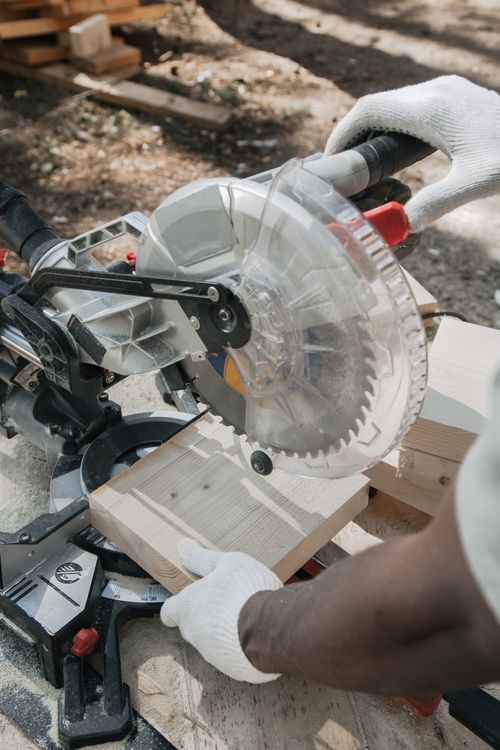 Free Close-up of a carpenter using a circular saw outdoors to cut wood, showcasing precision craftsmanship. Stock Photo