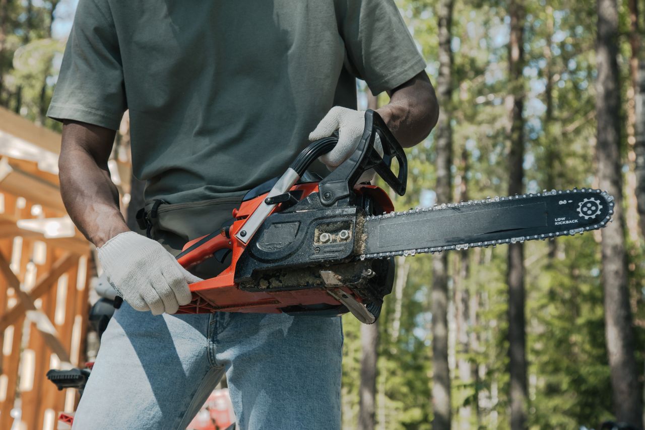 an adult holding a chainsaw outdoors showcasing forest work equipment