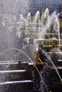 Woman in Black and Yellow Dress Sitting on Brown Wooden Chair in Front of Water Fountain
