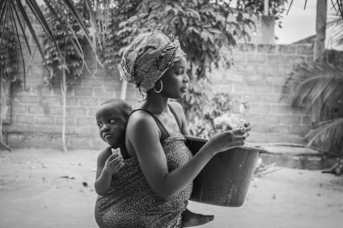 Monochrome Photo of Mother carrying her Son at her Back 