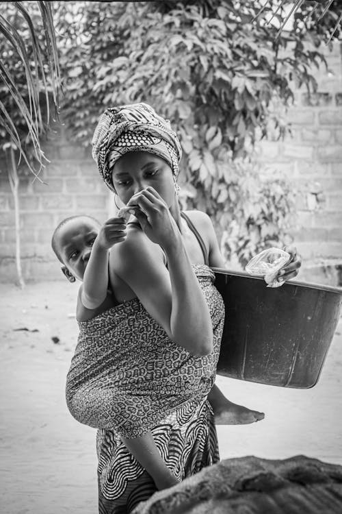 Monochrome Photo of Mother carrying her Son at her Back