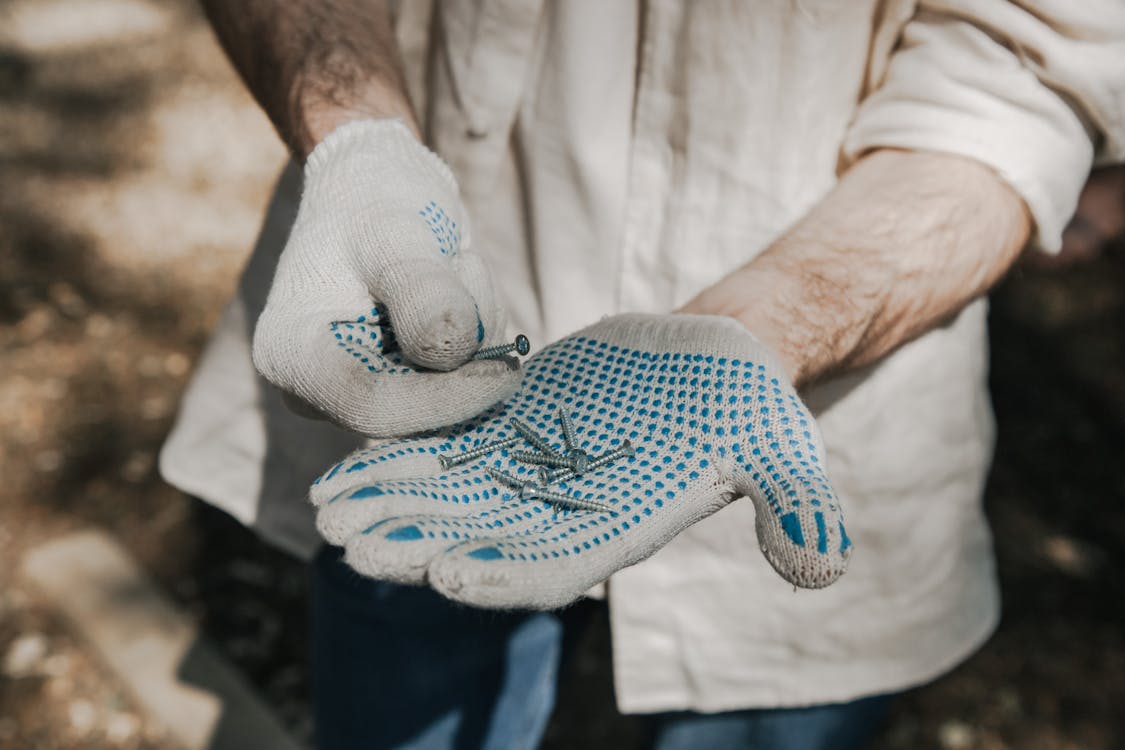 Person Wearing Protective Gloves Holding Silver Screws