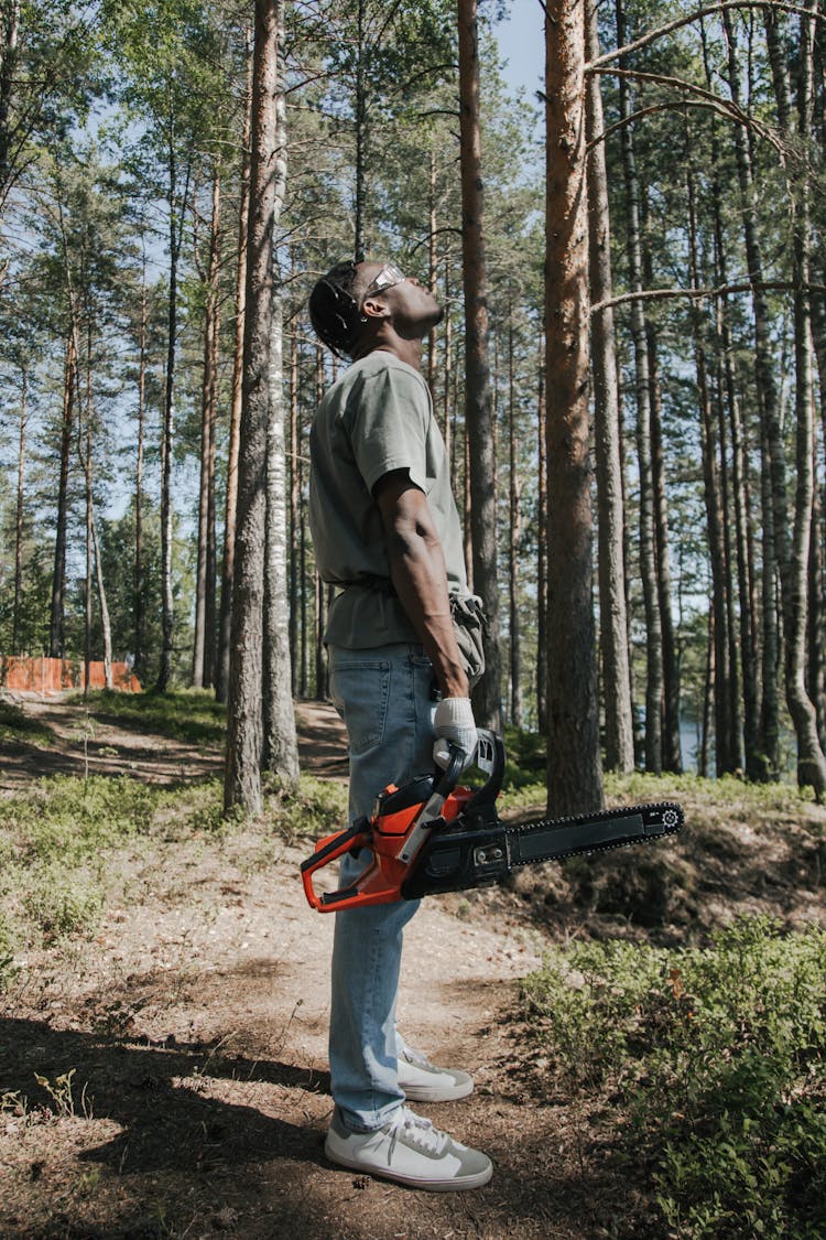 A Man In Gray Shirt Holding A Chainsaw