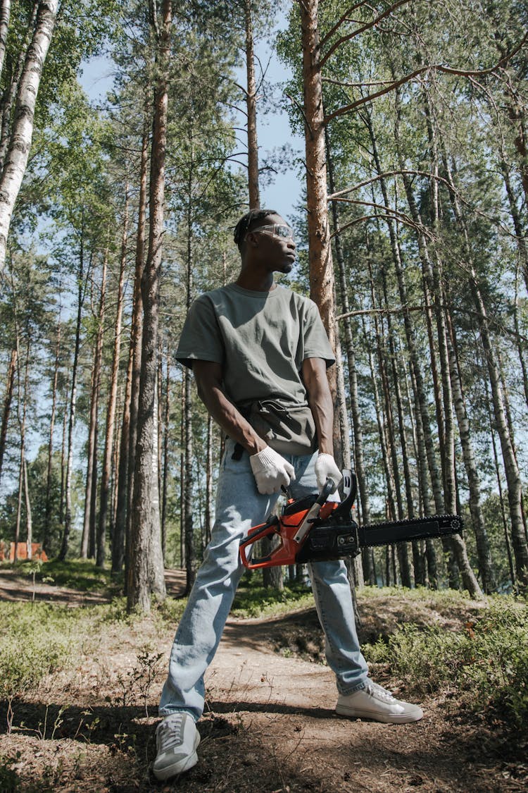 A Man In Gray Shirt Holding A Chainsaw