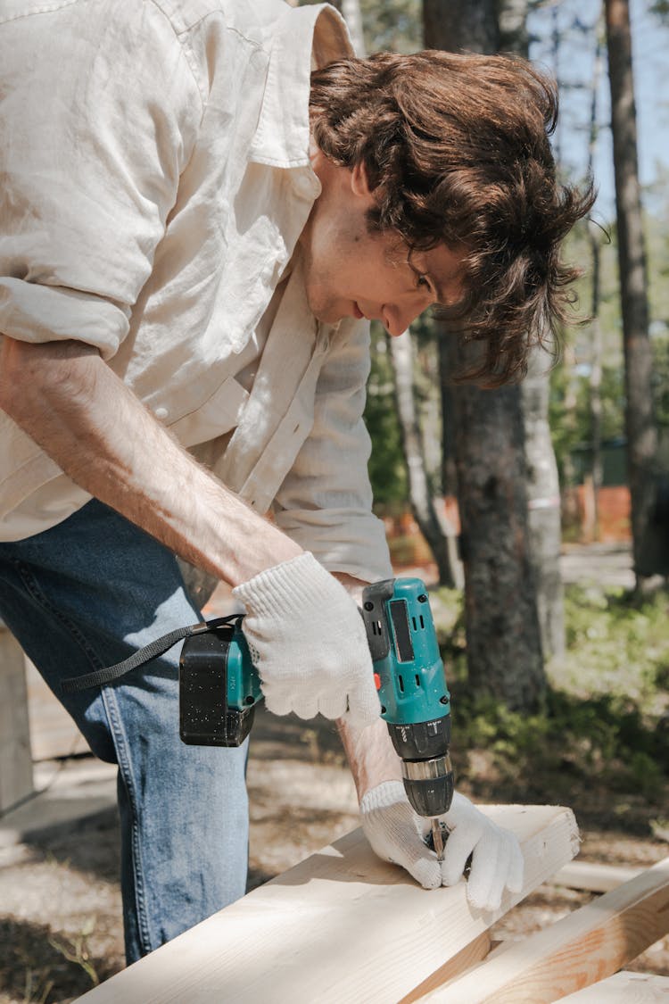 Man Using Hand Drill On A Wooden Panel