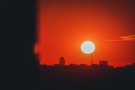 Stunning silhouette of city buildings against a vibrant sunset with a clear sky.