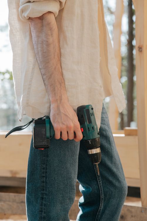 Free A carpenter holding a power drill at a construction site during daylight. Stock Photo