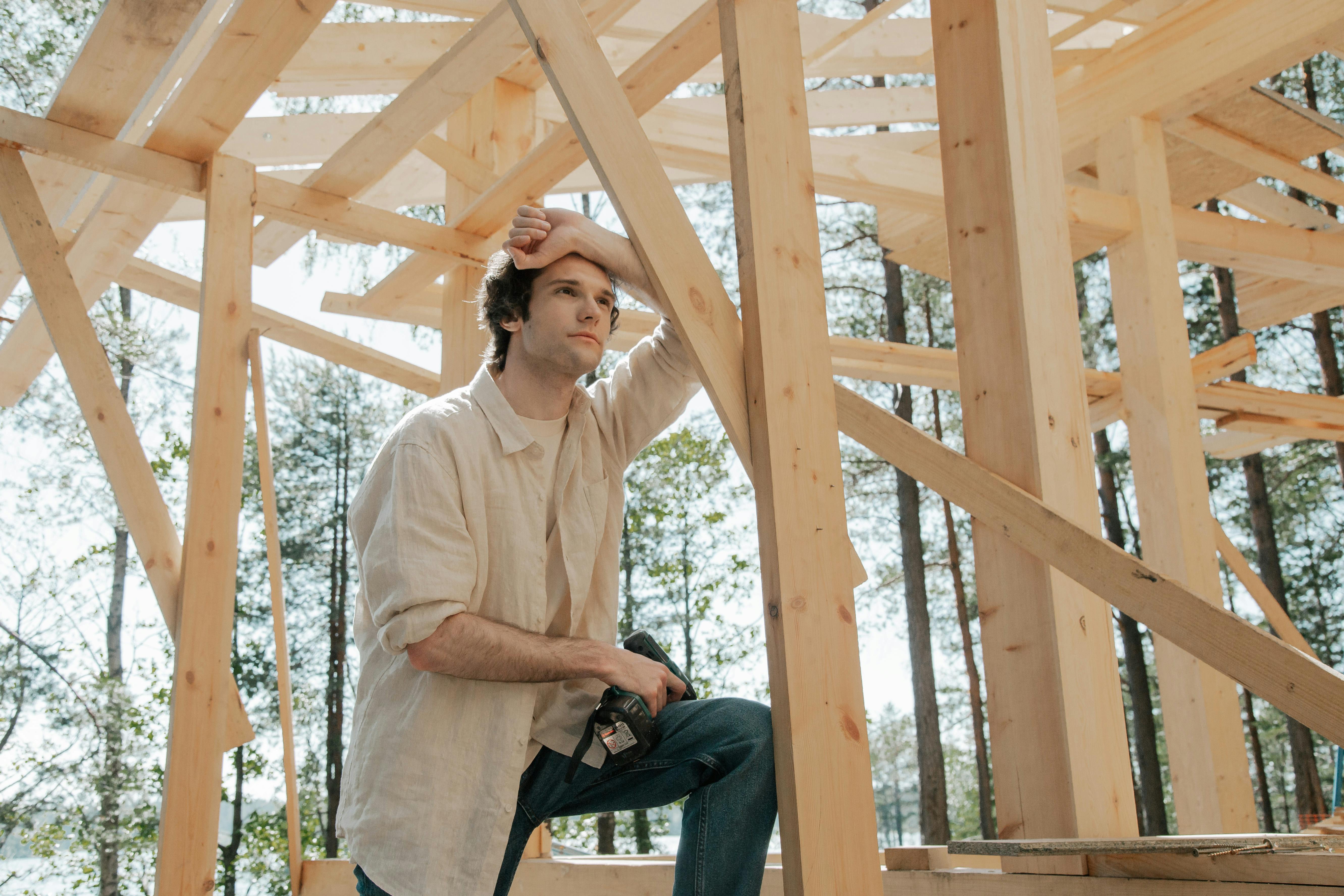 a man leaning on a wooden house frame