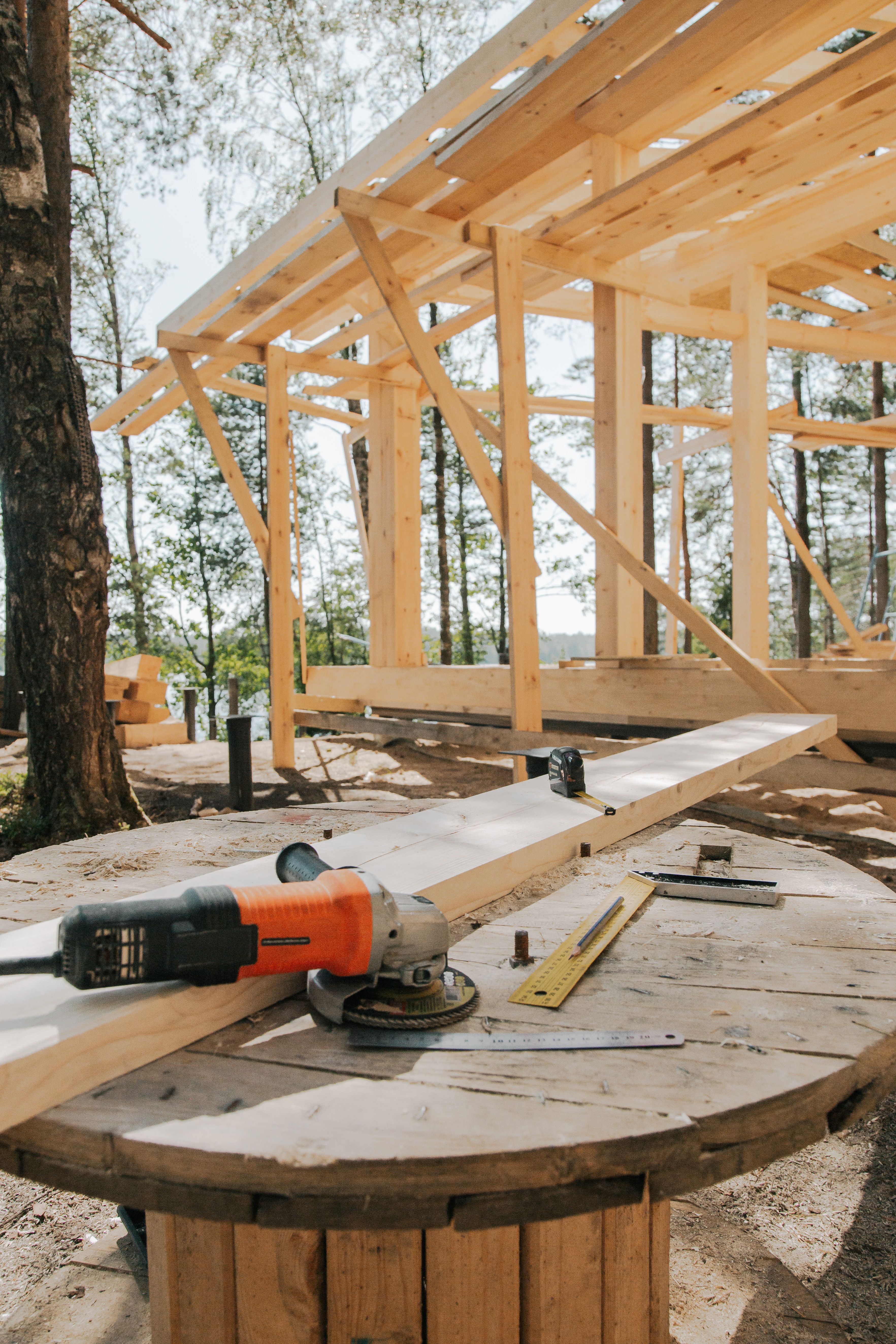 Partially built wooden house frame with tools and lumber on the ground under construction outdoors