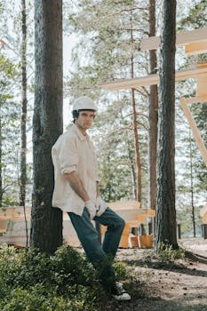 A young male construction worker with hard hat at a forest site.