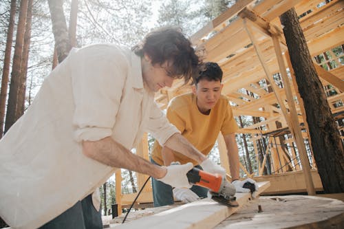 Men Using a Grinder on a Wood Plank