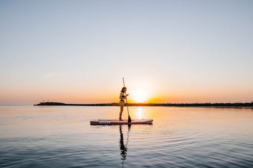 Free A Paddleboarder on the Sea during Sunset Stock Photo