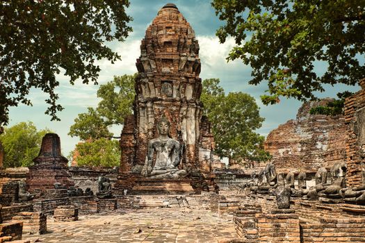 Explore the serene historical ruins of Ayutthaya featuring an ancient Buddha statue surrounded by lush greenery.