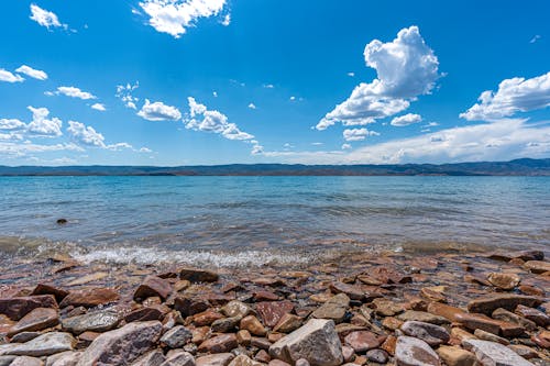 Free A Rocky Shore under Clear Blue Sky Stock Photo