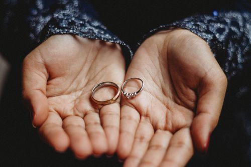Free Close-up image of hands delicately holding wedding rings, signifying love and union. Stock Photo