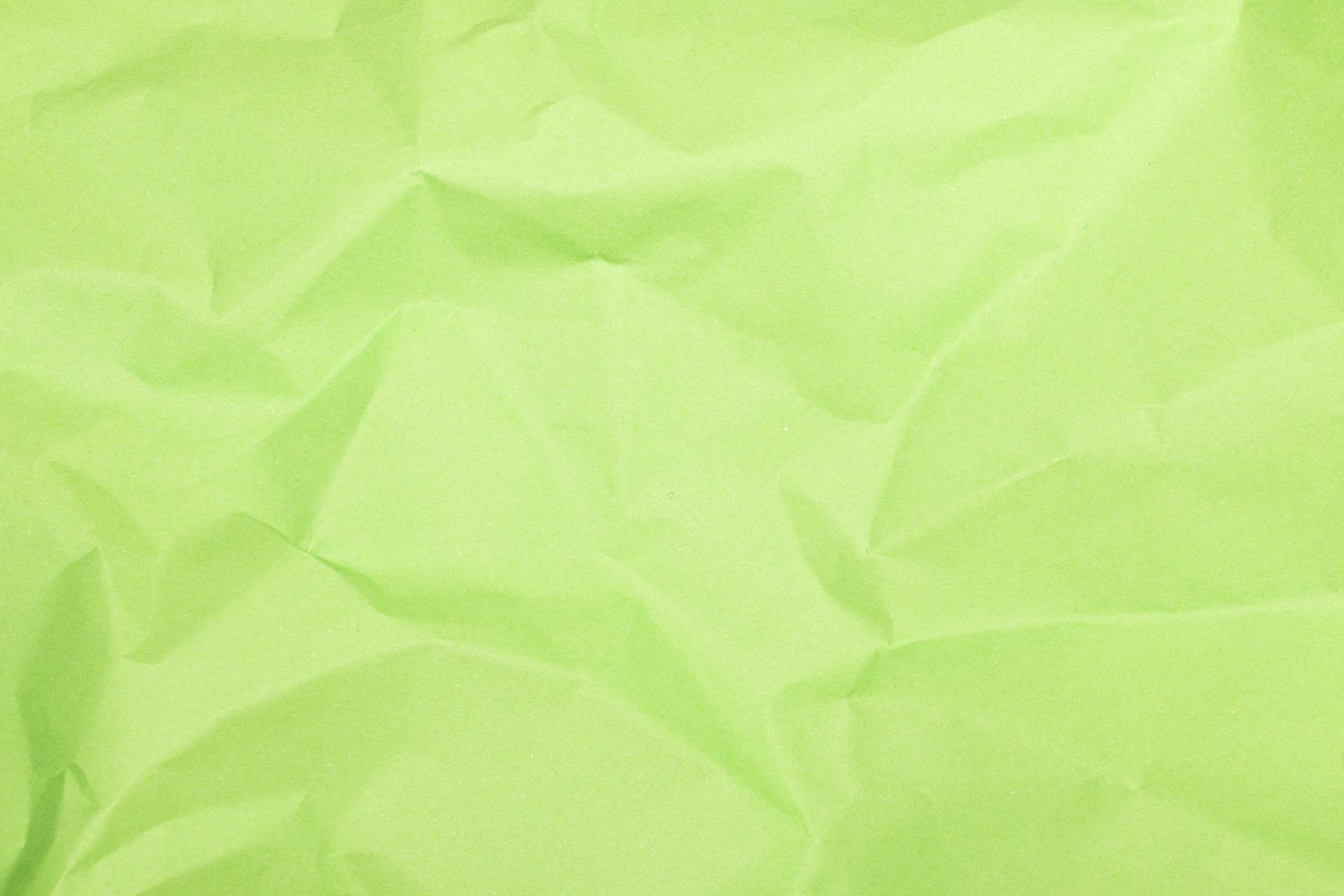 A close-up of crumpled green paper texture with natural folds and creases.