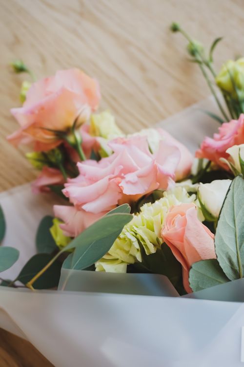 Free A close-up of a beautiful bouquet with pink and yellow roses on a wooden table. Stock Photo
